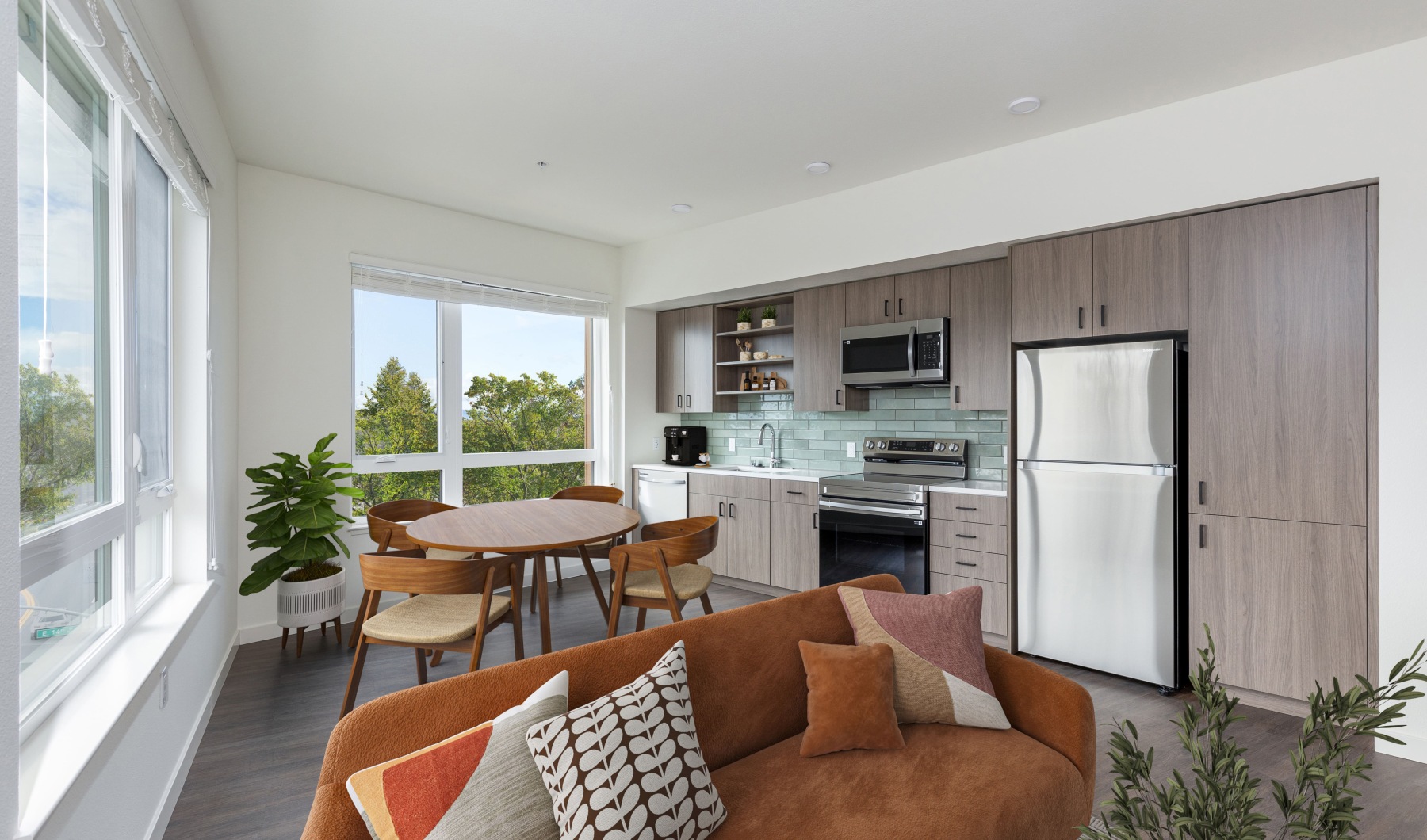 Staged photo of kitchen and dining area with stainless steel finishes and large windows