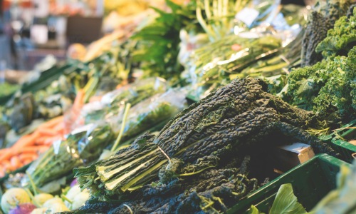 Fresh leafy greens and vegetables displayed at a market produce stand.